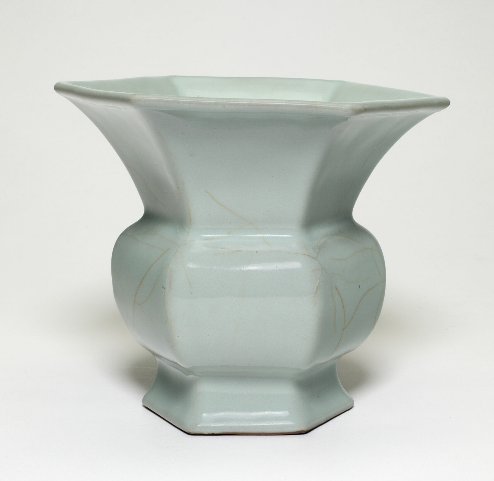 A pale celadon vase with a wide flared lip, six-sided body, and fine crackle lines.