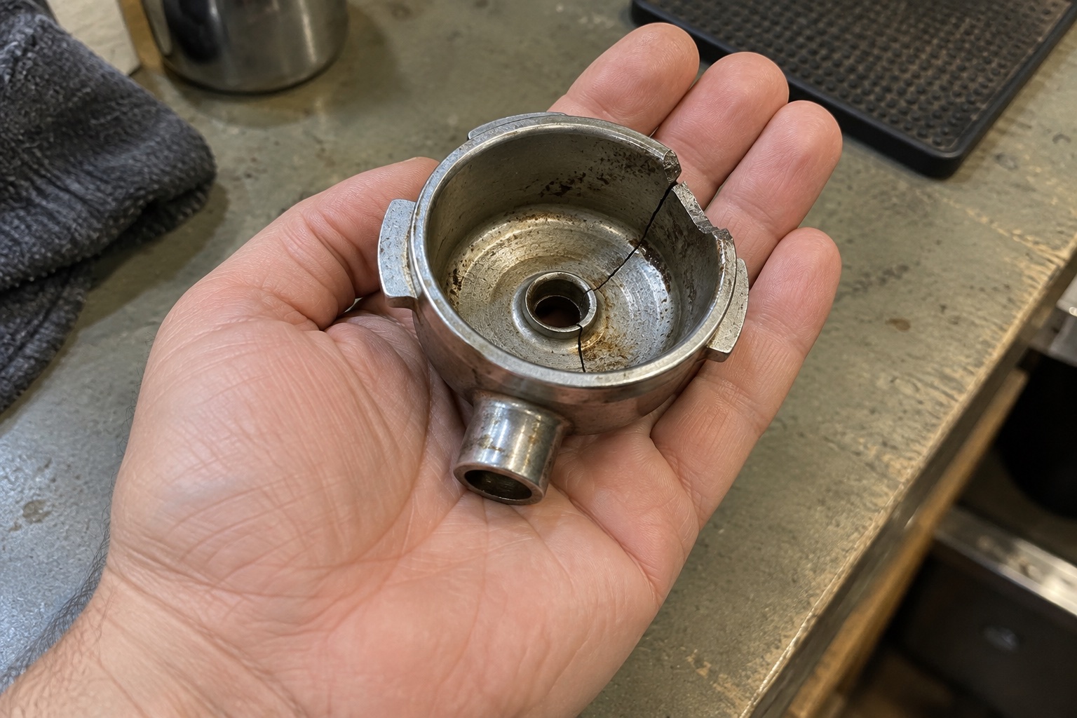 A cracked coffee-machine part in a palm