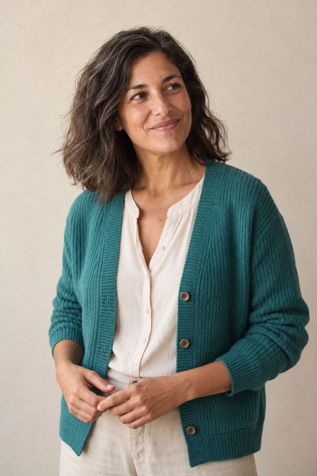 Ines, a fictional woman with shoulder-length dark hair, smiling off to one side in a sea-green cardigan.