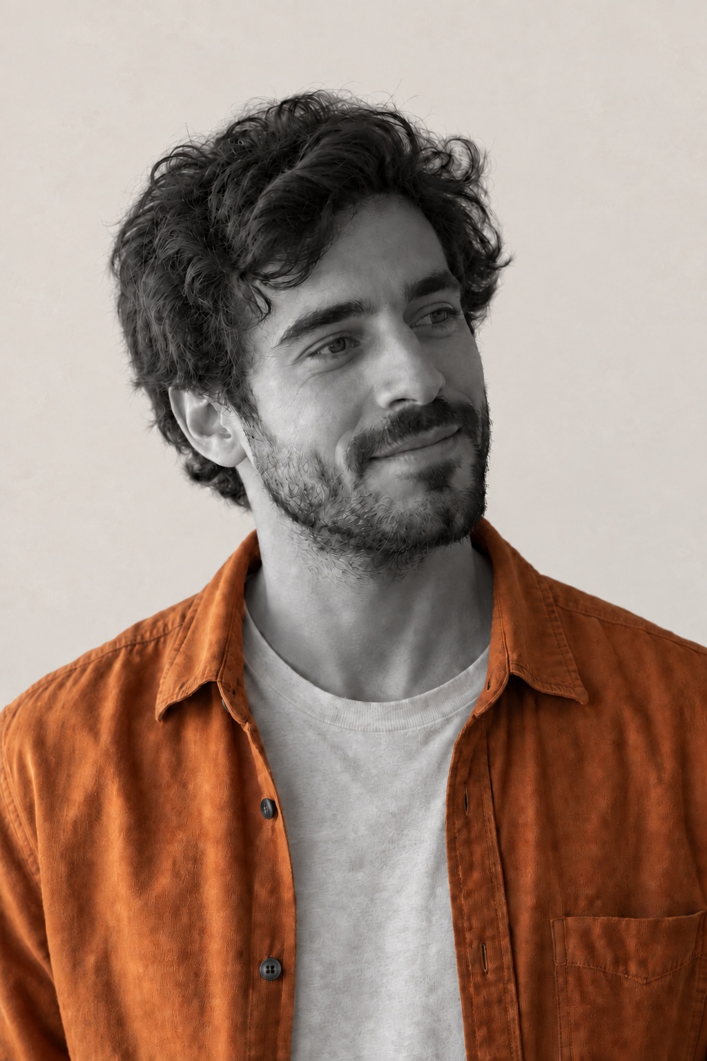 Theo, fictional, in his apricot overshirt, lit low from the left with the far side of his face in shade.