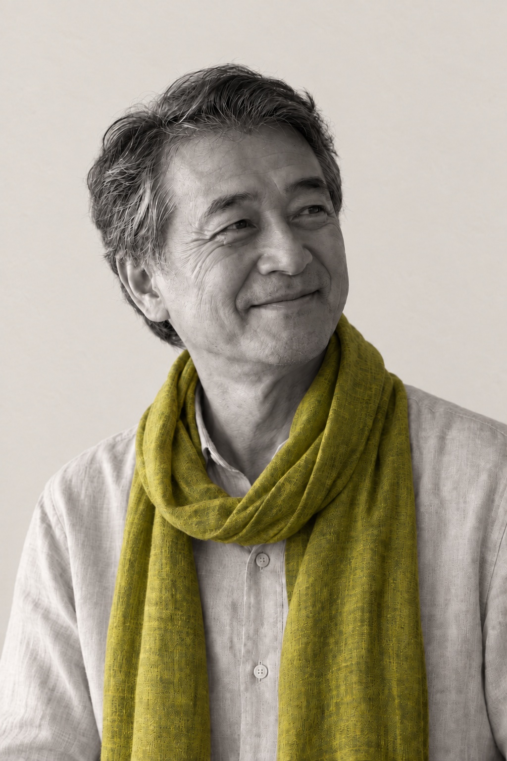 Jonah, fictional, smiling in his citron scarf, lit low from the left against shaded plaster.