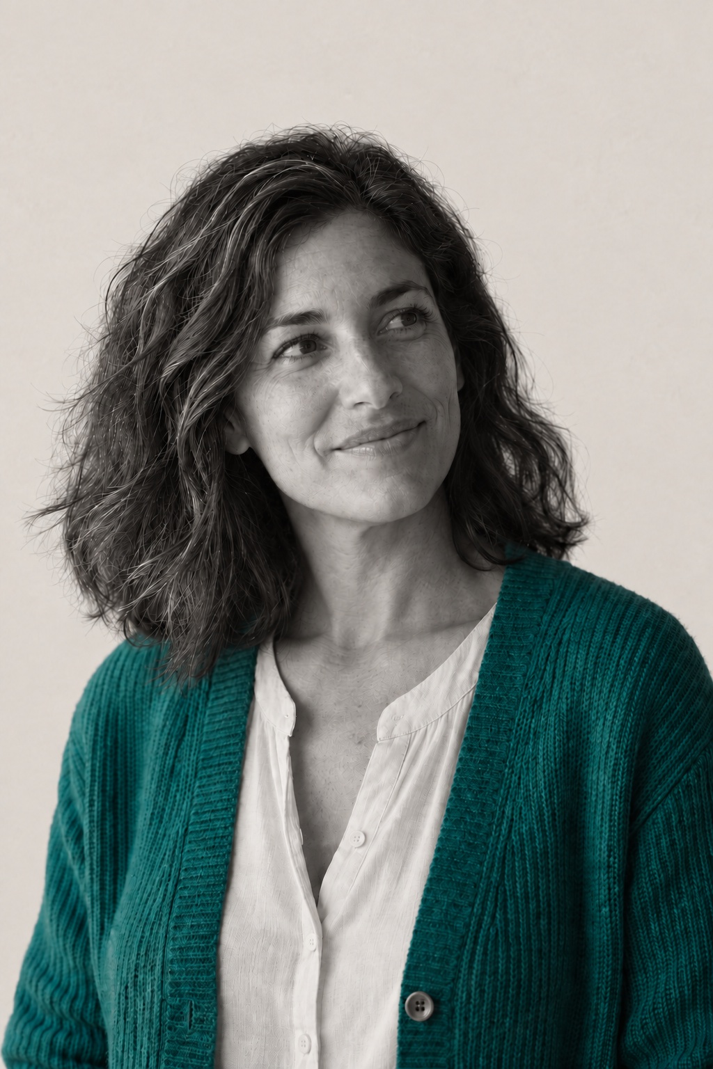 Ines, fictional, in her sea-green cardigan, looking off to one side in low evening light from the left.