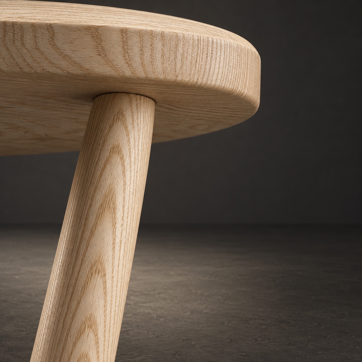 Looking up at one turned ash leg where its shoulder enters the underside of the seat in a round blind mortise.